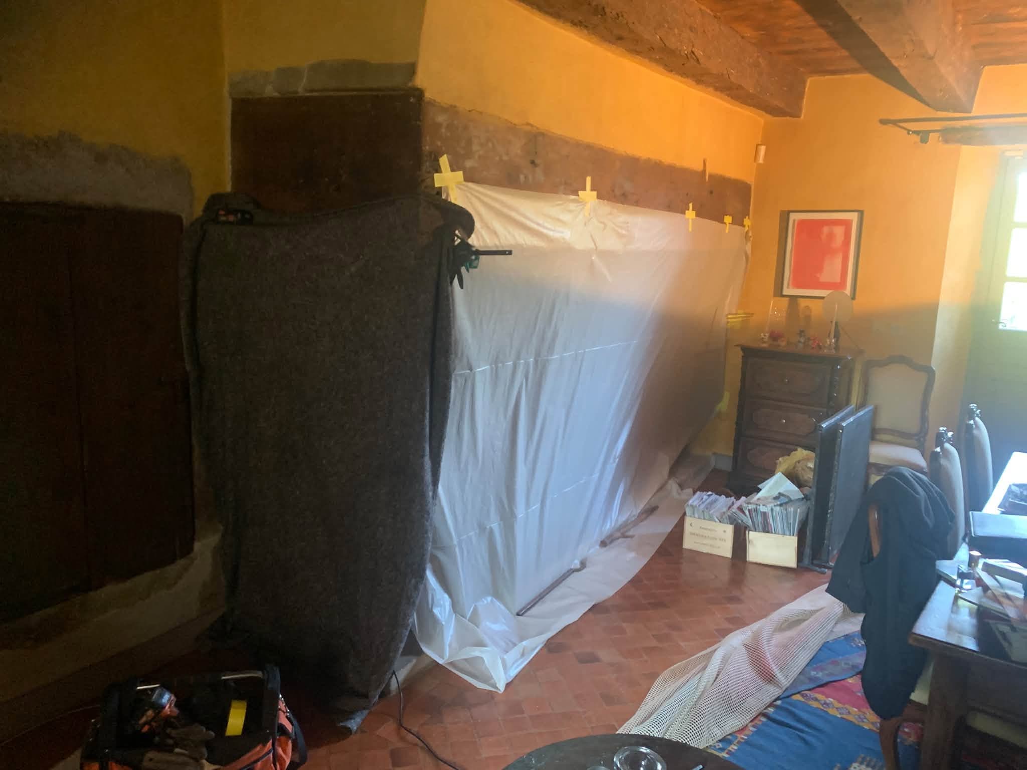 Bâche de protection installée contre un mur avant ramonage, intérieur protégé
